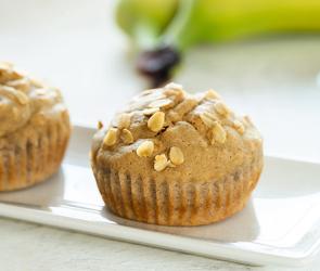 Zwei Bananenmuffins mit Ahornsirup auf einer Servierplatte.