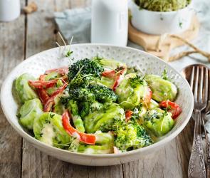 Basilikum-Gnocchi in Käsesauce auf einem Teller angerichtet.