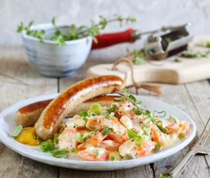 Bratwurst mit Rahm-Karotten auf einem Teller.