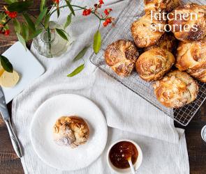Mehrere Brioche-Knoten mit Mandeln und Puderzucker in einer Schale und auf einem Teller.