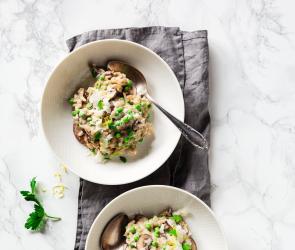 Cremiges Risotto mit Ricotta, Pilzen und Erbsen auf zwei Tellern