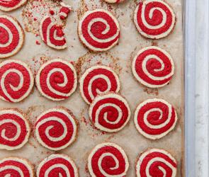 Mehrere Dinkel Zimtschnecken-Kekse rot-weiß auf einem Backblech.