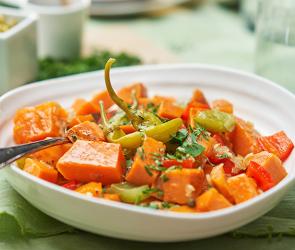 Eintopf aus Süßkartoffelwürfeln und Paprika auf Teller.