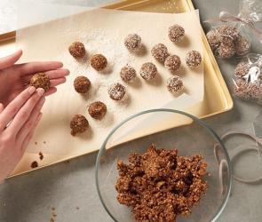 Energiekugeln mit Nüssen und Pflaumen werden geformt und auf ein Backblech gelegt.