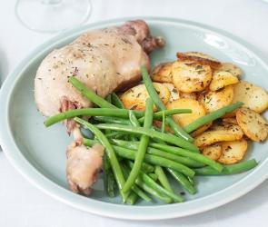 Enten-Confit mit Bratkartoffeln und Bohnen auf einem Teller.