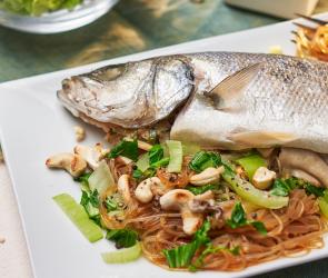 Fisch gedämpft asiatisch mit Glasnudeln auf einem Teller.
