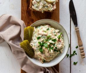 Brett mit belegten Broten und Fleischsalat in Schälchen