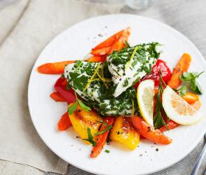 Gedämpftes Zitronen-Kräuter-Hähnchen auf Gemüse auf einem Teller serviert.