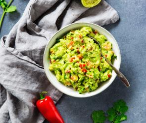 Guacamole in Schüssel, Tuch, Limette und Chilischote