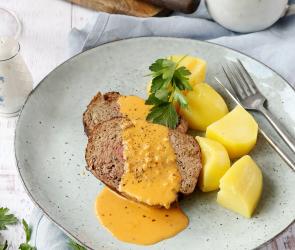 Hackbraten mit roter Soße und Kartoffeln auf einem Teller.