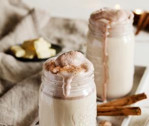 Heiße weiße Schokolade mit Kakaosahne in einem hohen Glas.