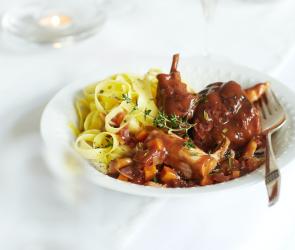 Nudeln und Kaninchenfleisch in einer Schüssel mit Sauce. 