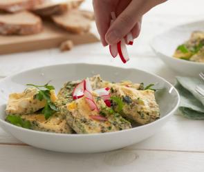 Käse-Kräuter-Omelett in Stücken mit Radieschen in einem Teller.