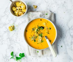 Karotten mit Sesam-Blumenkohl-Topping in einer Schüssel angerichtet.