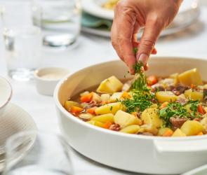 Kartoffelgulasch deftig in einer Schale, wird mit Petersilie garniert.