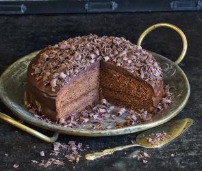 Klassische Sachertorte angeschnitten auf einer Kuchenplatte.