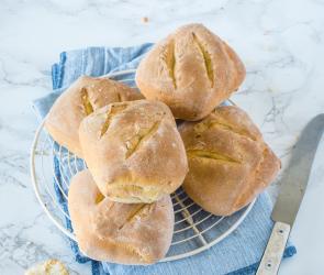 Mehrere Dinkelbrötchen aus dem Cookit mit Messer auf Marmortisch.