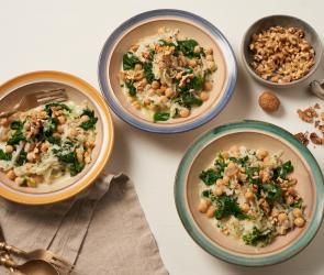 Kohlrabi mit Blattspinat und Kichererbsen in drei Tellern auf einem Tisch.