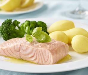 Lachsfilet gedämpft mit Brokkoli und Kartoffeln auf einem Teller.