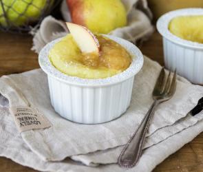 Luftiges Vanille-Soufflé mit Apfel in einem Förmchen auf einem Tisch.