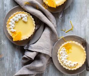 Drei Mini-Käsekuchen auf drei Tellern mit Kuchengabeln und Tuch