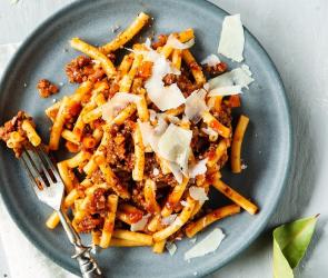 Pasta Bolognese auf Teller mit Parmesan und Basilikum garniert