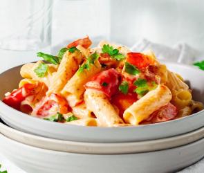 Nudeln mit Sauce und Petersilie auf drei tiefen Tellern