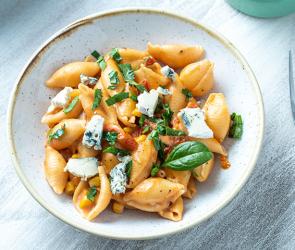 One-Pot-Pasta mit Tomaten, Mais und Blauschimmelkäse in einem Teller.