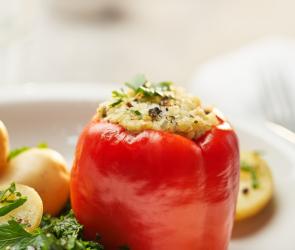 Paprikaschoten gefüllt mit Bulgur auf Blattspinat auf einem Teller.