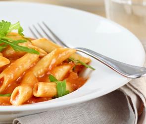 Penne-Pomodoro mit Gorgonzola und Rucola in einem Teller angerichtet.