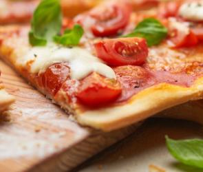 Pizza Margherita angeschnitten auf einem Holzbrett.