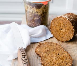 Pumpernickel im Glas, daneben ein Brot in Scheiben geschnitten.