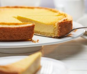 Quark-Vanille-Torte angeschnitten auf einer Kuchenplatte und als Stück auf einem Teller.