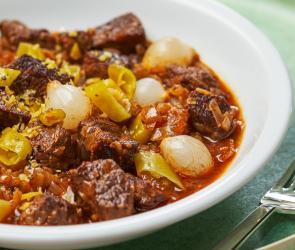 Rindergulasch mit Perlzwiebeln aus dem Cookit auf einem Teller angerichtet.