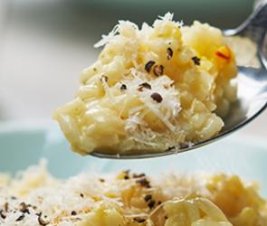 Risotto Milanese wir mit einem Löffel aus einer Schale genommen.