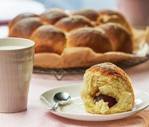 Rohrnudeln mit Zwetschgenfüllung auf einem Teller, daneben ein Becher.