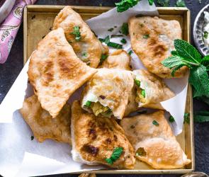 Samosas mit Gemüsefüllung und Minz-Joghurt auf einem Teller