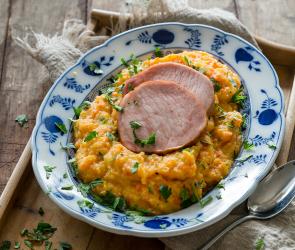 Steckrübenmus mit Kasseler auf einem Teller angerichtet.