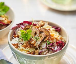 Steinpilz-Risotto mit karamellisierten Walnüssen in einer Schale angerichtet.
