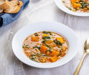 Süßkartoffel- und Kichererbsen-Curry mit Spinat auf Tellern.