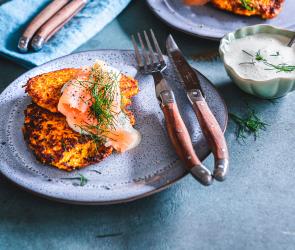 Süßkartoffelpuffer mit Lachstopping auf einem Teller.
