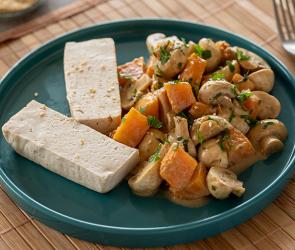 Tofu gedämpft mit Kürbis und Champignons auf einem Teller.