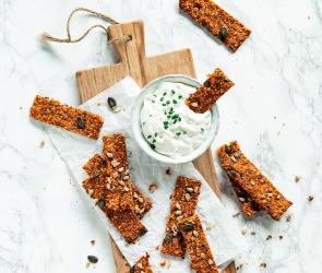Mehrere Tomaten-Karotten-Cracker mit Pesto auf Schiefertafel.