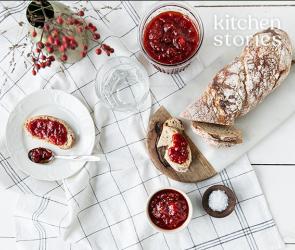 Tomatenmarmelade auf Brotscheiben und in einem Töpfchen auf einem Tisch.