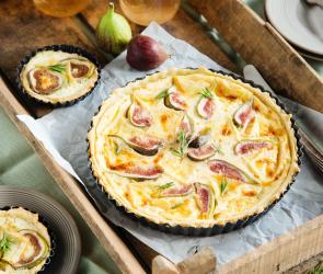 Ziegenkäse-Feigen-Quiche auf einem Holzbrett. 