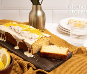 Zitronenlaibkuchen auf Servierteller mit angeschnittenen Scheiben und Zitronen