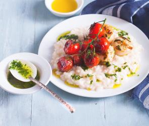 Zitronenrisotto mit Jacobsmuscheln und Kirschtomaten auf einem Teller.
