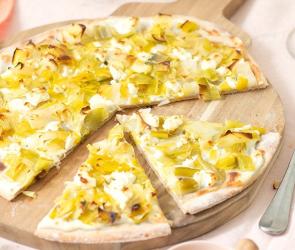 Flammkuchen mit Lauch auf einem Holzbrett.