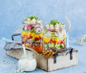 Bunter Schichtsalat mit Kichererbsen und Joghurtdressing im Glas geschichtet.
