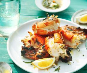 Grillgarnelen in Kräutermarinade mit Zitronenvierteln auf einem Teller angerichtet.